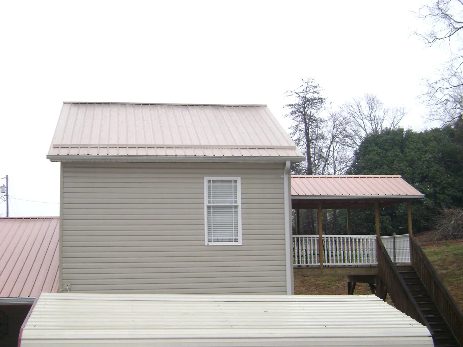 Tan metal roofs on a two story addition and attached porch, from a Roof Replacement job in Union